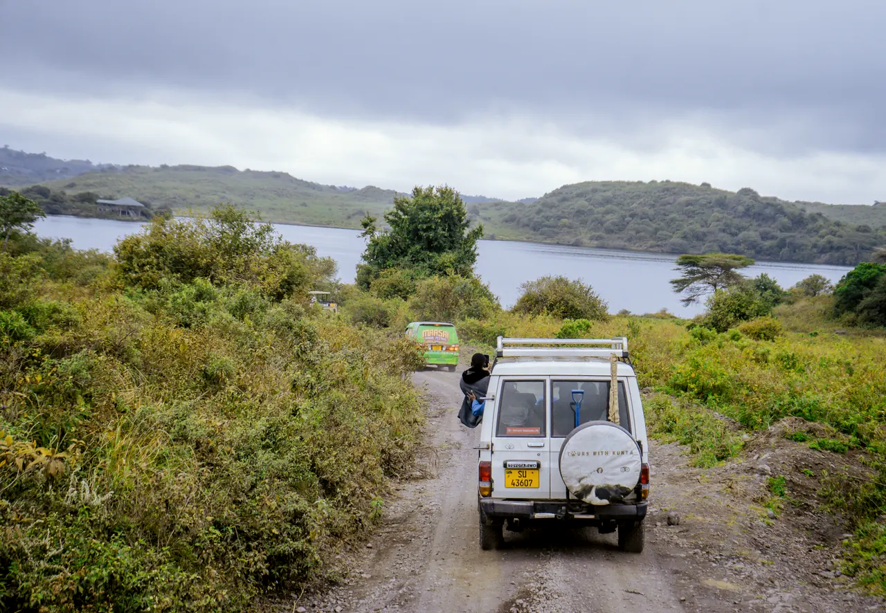 Safari vehicle on a track above a lake in Arusha National Park